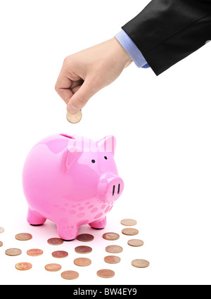 Una mano l'inserimento di una moneta in un rosa salvadanaio Foto Stock
