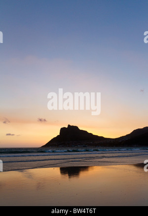 Tramonto su Hout Bay, Città del Capo, Sud Africa, mostrando leopard-roccia a forma riflessa nella sabbia bagnata Foto Stock