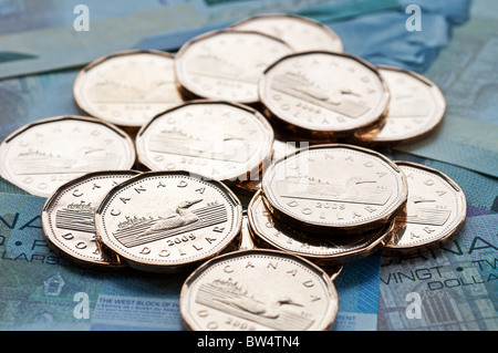 Un angolo alto vista ravvicinata del canadese un dollaro, comunemente noto come 'loonie', monete sulla parte superiore di cinque e venti le fatture del dollaro. Foto Stock