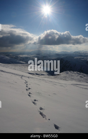 Il sole invernale e Orme nella neve su Helvellyn, montagna nel Lake District inglese Foto Stock