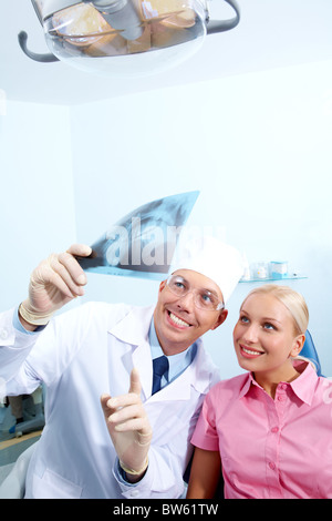 Immagine del dentista che mostra x-ray fotografia al paziente in esame medico Foto Stock