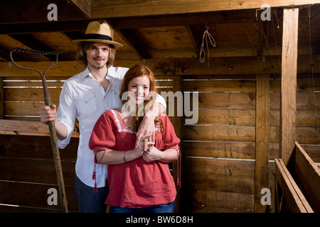 Coppia giovane in agriturismo in piedi all'interno di un fienile Foto Stock