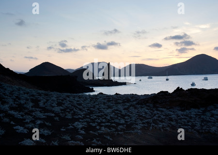 Vista del pinnacolo di roccia e tour ormeggiate barche al tramonto, Bartolome Island, Galapagos. Foto Stock