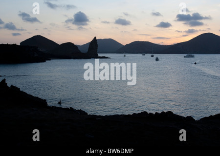 Vista del pinnacolo di roccia e tour ormeggiate barche al tramonto, Bartolome Island, Galapagos. Foto Stock