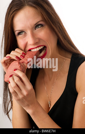 Bella Donna morde un pezzo grezzo di carni bovine Foto Stock