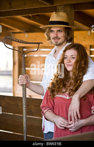 Coppia giovane in agriturismo in piedi all'interno di un fienile Foto Stock