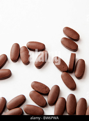 Generico pillole marrone versato all'esterno su bianco Foto Stock