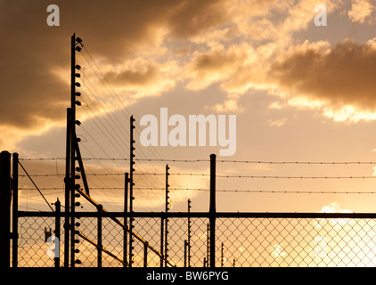 Grandi recinti e filo spinato contro un Cielo di tramonto con spazio di copia Foto Stock