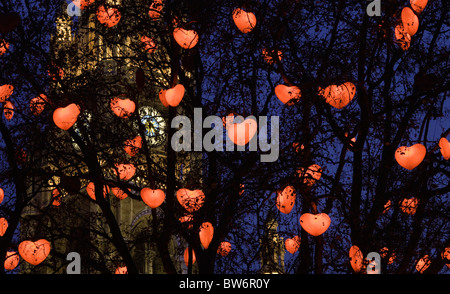 Cuore a forma di luci appendere in alberi che circondano il mercatino di Natale di Rathausplatz di Vienna Foto Stock