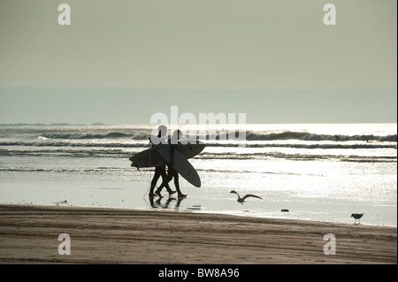 Surfers passeggiate a mare a Condino Devon UK Foto Stock