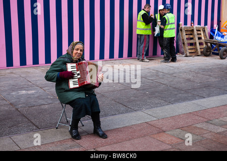 Donna rumena musicista di strada nel centro della città di Glasgow al di fuori di un edificio sito e ignorando tutti i suoi Foto Stock