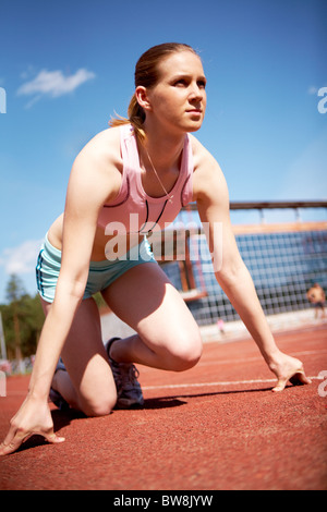 Immagine del giovane femmina pronta per iniziare a correre mentre sul Stadium Foto Stock