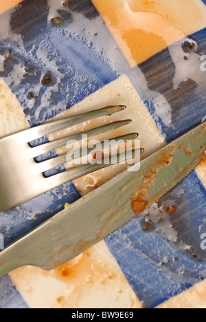 Coltello e forchetta su un vuoto piastra sporca dopo aver mangiato la cena Foto Stock