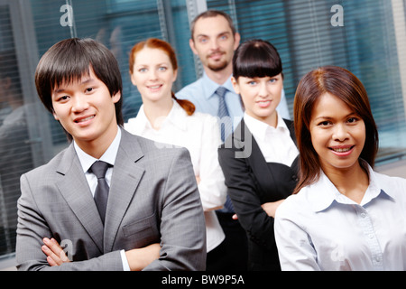 Foto di business di successo partner guardando la fotocamera con co-lavoratori dietro di loro Foto Stock