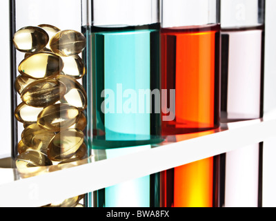 Fila di provette riempite di liquido colorato, uno riempito con gel vitamine cap. Foto Stock