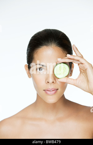 Donna che mantiene il cetriolo over eye Foto Stock