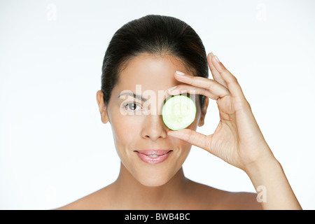 Donna che mantiene il cetriolo over eye Foto Stock