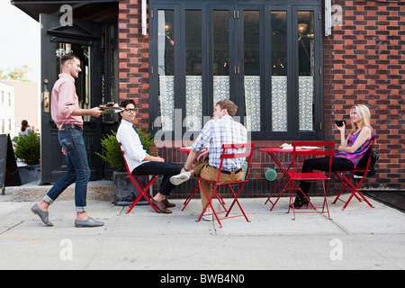 Cameriere con caffè per le persone al di fuori del cafe Foto Stock