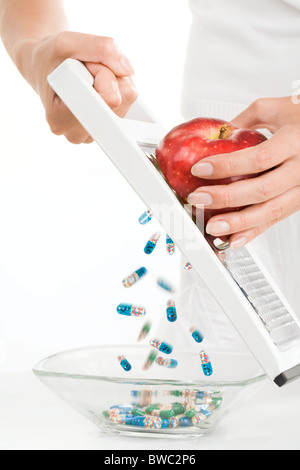 Close-up di vitamine e pillole riversandosi nel vaso mentre il reticolo femmina rosso apple Foto Stock