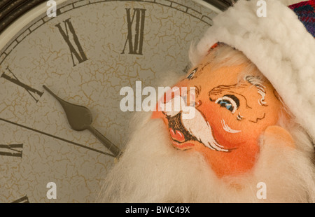 Tessuto dipinto Babbo Natale faccia con grande orologio sullo sfondo. Santa all'orologio. L'orologio si avvicina a 12. Foto Stock