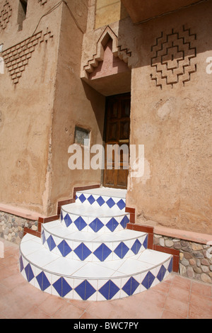 In piastrelle colorate gradini che conducono ad una porta di legno in una città del Marocco Foto Stock