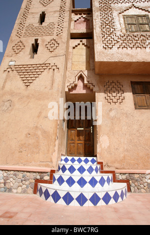 In piastrelle colorate gradini che conducono ad una porta di legno in una città del Marocco Foto Stock