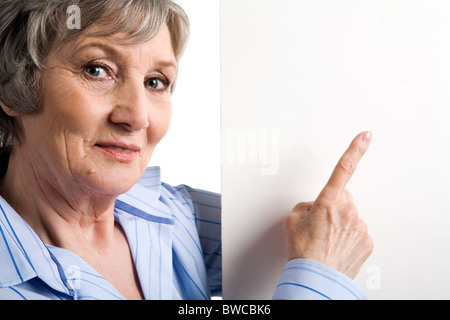 Immagine di anziani di sesso femminile a puntamento copyspace vuoto e guardando la fotocamera Foto Stock