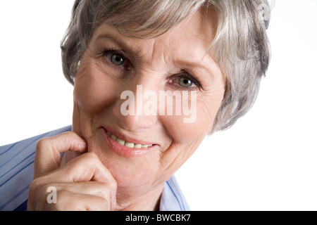 Foto di donne più anziane di toccare il suo mento e guardando la fotocamera su sfondo bianco Foto Stock