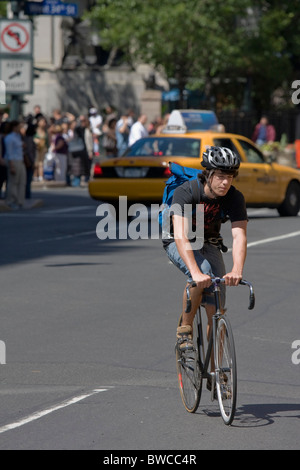 New York, 28 Maggio 2009: un uomo in bicicletta attraverso Manhattan, nella parte posteriore di un taxi giallo Foto Stock