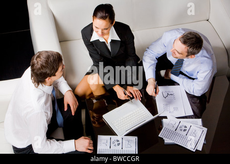 Tre partner soggiorno d'affari seduti attorno al tavolo e i lavori di pianificazione a briefing Foto Stock