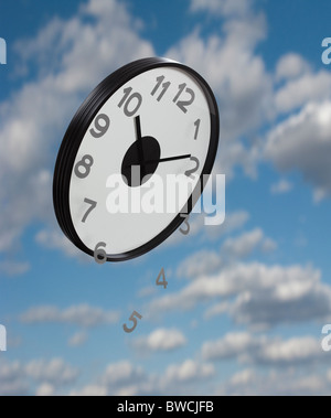 Numeri che rientrano dal clock battenti contro il cielo, composito digitale Foto Stock