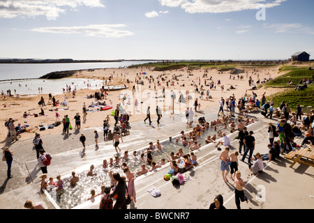 Le persone che si godono la giornata in spiaggia Nautholsvik, Reykjavik, Islanda. L'acqua della laguna è riscaldato con acqua geotermica. Foto Stock