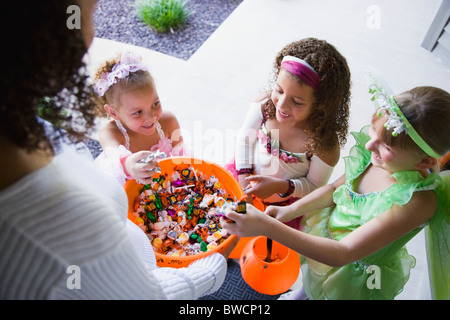 Stati Uniti d'America, Illinois, Metamora, giovane donna dando caramelle per ragazze (6-7, 8-9) in costumi durante il periodo di Halloween Foto Stock