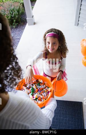 Stati Uniti d'America, Illinois, Metamora, giovane donna dando caramelle alla ragazza (8-9) in costume durante il periodo di Halloween Foto Stock