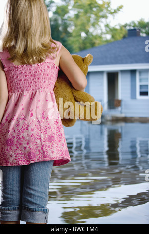 Stati Uniti d'America, Illinois, Chillicothe, ragazza (6-7) in piedi in acqua e portando Teddy bear, vista posteriore Foto Stock