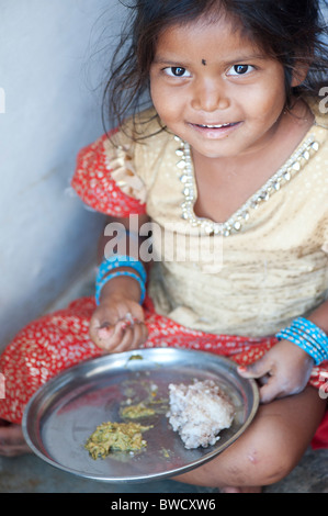 Indiano piccolo villaggio rurale ragazza mangia stracci palla per colazione, alla porta di casa sua. Andhra Pradesh, India Foto Stock