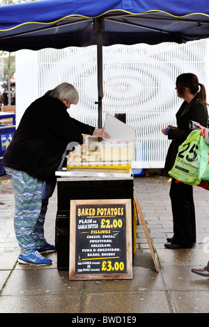 Donna tradizionale di vendita patate al forno in un mercatino di natale in Portsmouth Inghilterra Regno Unito Foto Stock