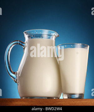 Il vetro e il vasetto di latte su uno sfondo blu. Foto Stock