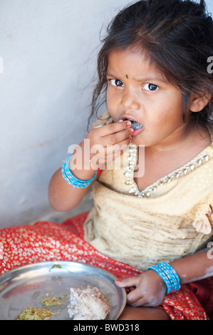 Indiano piccolo villaggio rurale ragazza mangia stracci palla per colazione, alla porta di casa sua. Andhra Pradesh, India Foto Stock