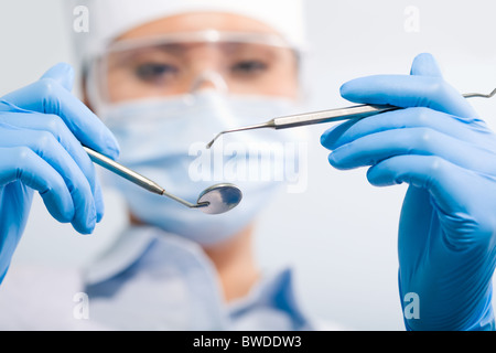 Immagine di assistente nella maschera sterile tenendo in odontoiatria gli utensili a mano Foto Stock