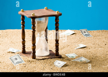 Immagine della clessidra e diversi hudred dollar banconote Vicino sulla sabbia Foto Stock