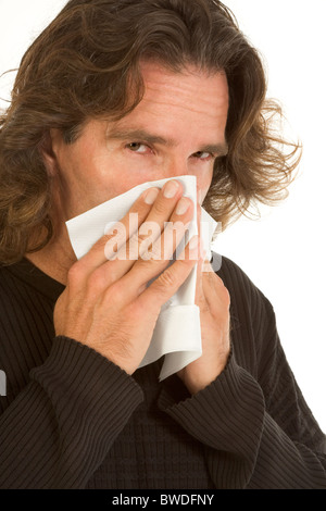 Di mezza età maschio copre il suo naso e parte del viso con un tovagliolo di carta o tessuto apparentemente soffiando il suo Foto Stock