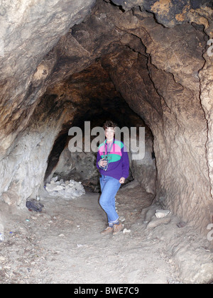 Una donna cammina lungo le scogliere e la grotta city Foto Stock