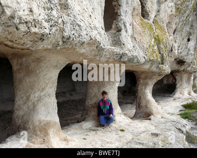 Una donna cammina lungo le scogliere e la grotta city Foto Stock