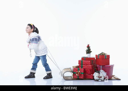 Ragazza tirando la slitta che i regali di Natale erano su di esso Foto Stock