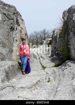 Una donna cammina lungo le scogliere e la grotta city Foto Stock