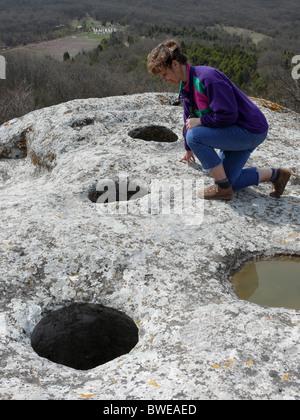 Una donna cammina lungo le scogliere e la grotta city Foto Stock