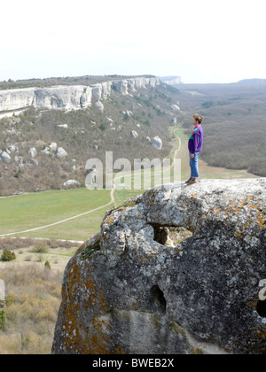 Una donna cammina lungo le scogliere e la grotta city Foto Stock