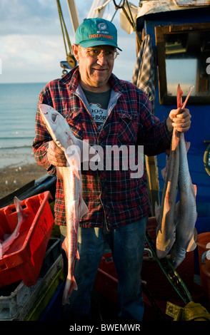 Lavoro duro ai pescatori che arrivano con la loro notte di catch all'alba nella loro barca sulla spiaggia a Hastings Old Town East Sussex. Foto Stock