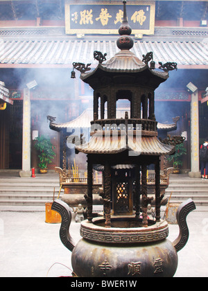 All'interno di un tempio buddista di Hangzhou in Cina, con fumo proveniente dalla brace ardente di incenso Foto Stock